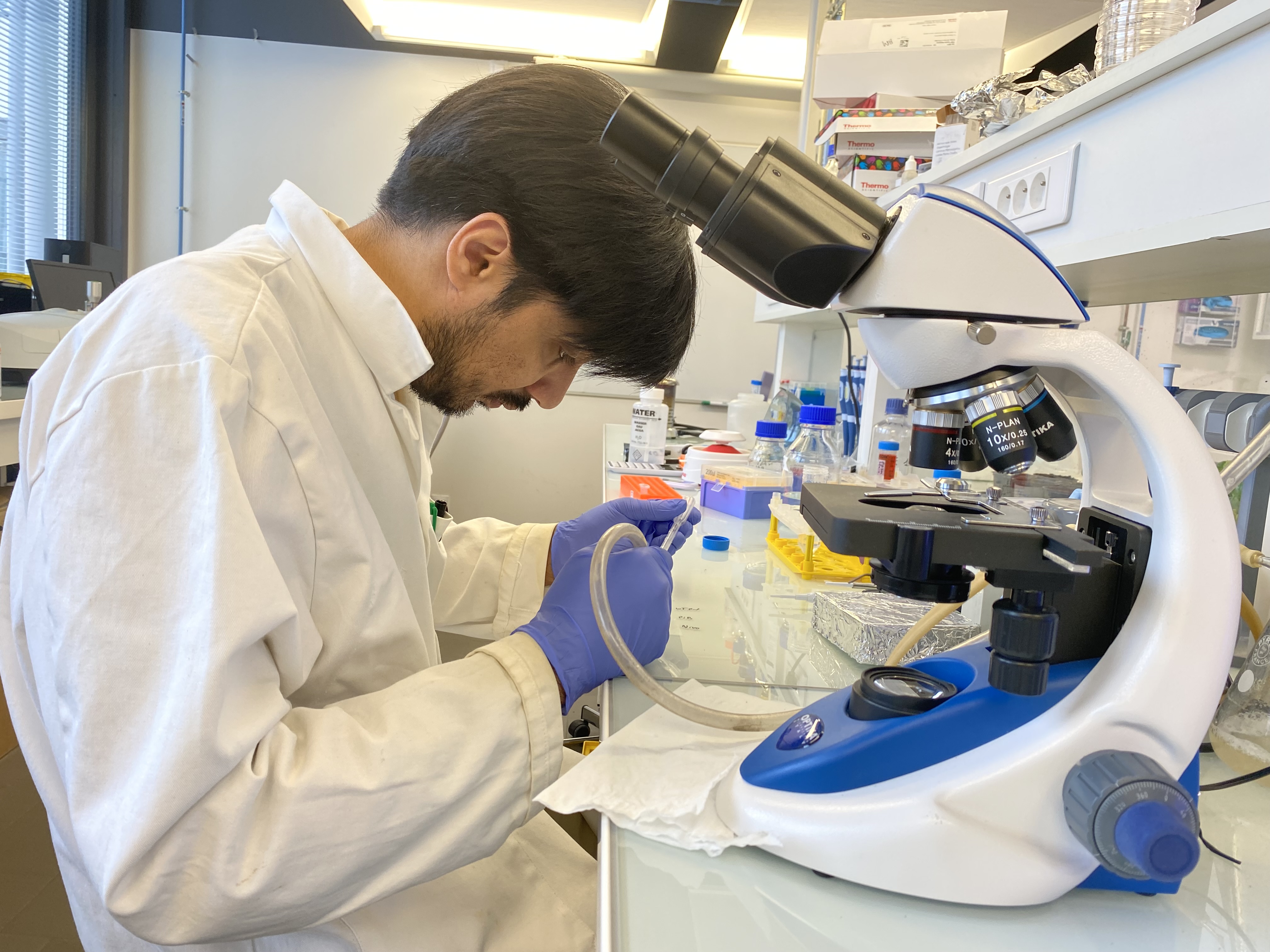 Bilal Mazhar working with microscope and lab equipment